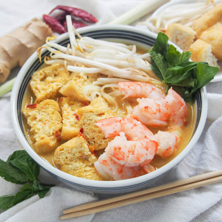 bowl of Singapore laksa with chopsticks under bowl.